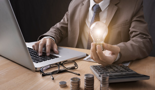 Business man hand holding lightbulb with using calculator to calculate. concept idea saving finance.